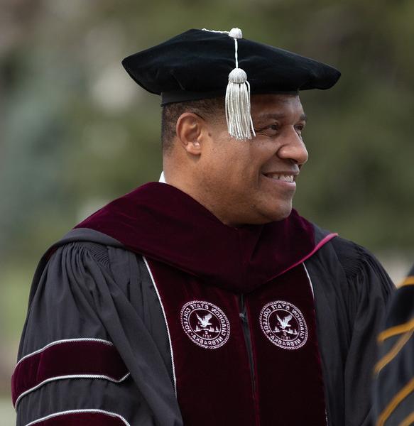 Adult male in academic regalia outdoors